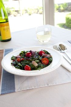 Warm spinach salad with cherry tomatoes and red onions.