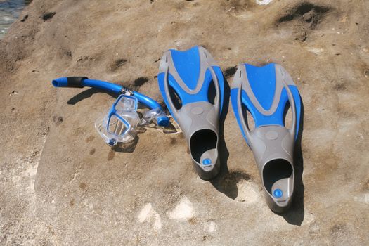 Flippers and snorkel with the mask lying on a rock.