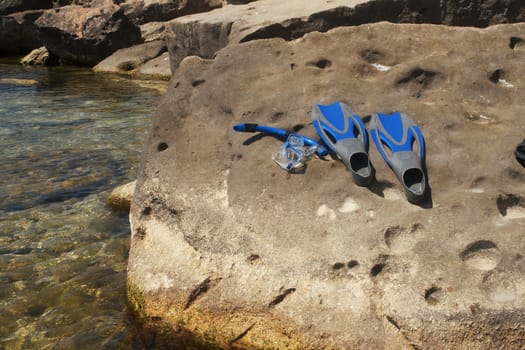 Flippers and snorkel with the mask lying on a rock.