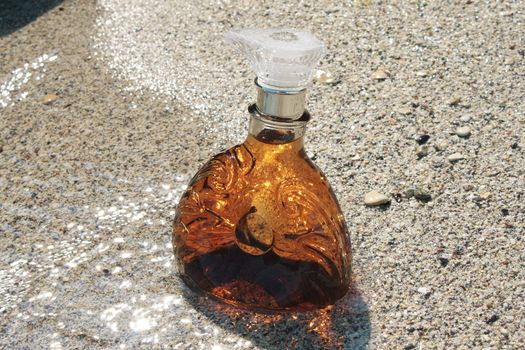 A bottle of cognac on the sandy beach.