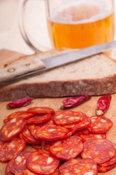 Slices of Hungarian Sausage on Chopping Board With Chilies, Bread and Glass of Beer