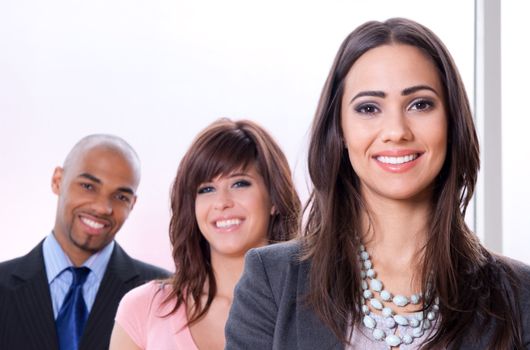 Young and successful business team, three smiling people of different races.