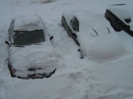 A photograph of cars covered in heavy snow.