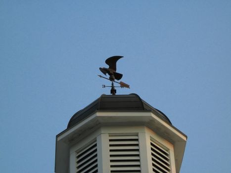 A photograph of a weather vane on top of a tower.