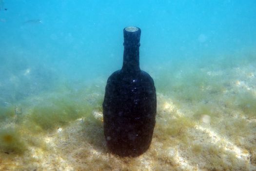 Sealed bottle of wine under the water on the seabed.