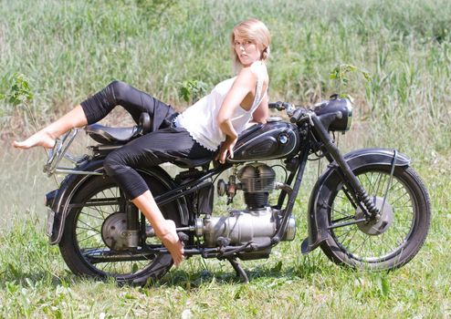 Fashionably dressed woman seated on an old motorcycle