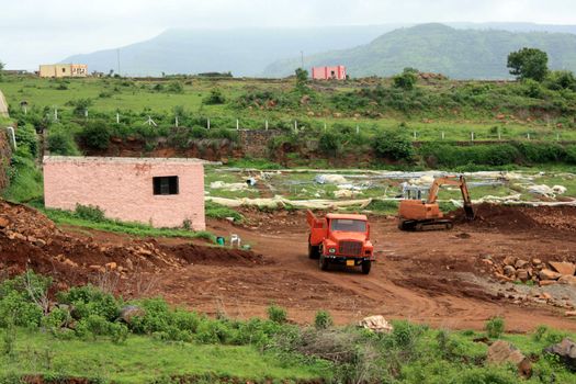 Construction machinery in a newly fenced plot starting with foundation construction.