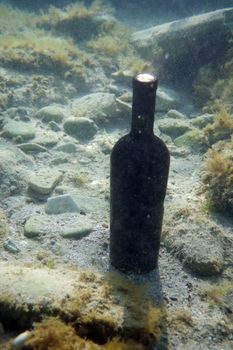 Sealed bottle of wine under the water on the seabed.