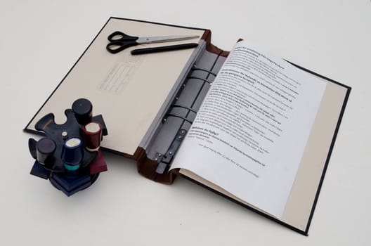 ring binder with paper, scissors, pen, stamps and paper on a desk