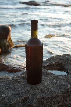 Wine in the bottle stands on a rock against the sky.