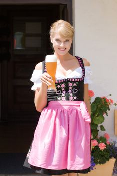 Young woman in dirndl wheat beer served in a mountain economy