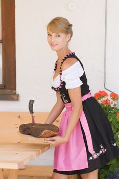 Bavarian Dirndl woman serving a bacon on a plate Alm