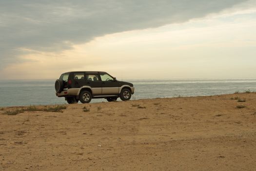 Jeep car is on the edge of the cliff against the sea.