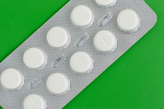 Macro view of white pills on green background.