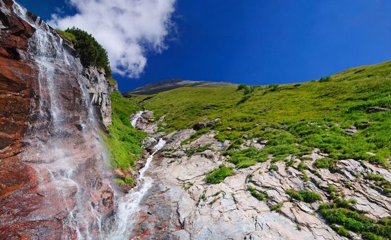 Alpine waterfall with rocks and a forest