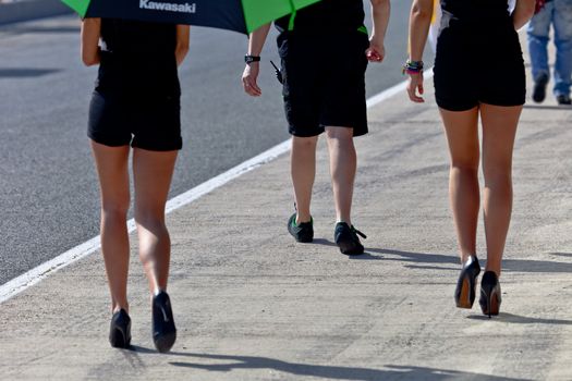 JEREZ DE LA FRONTERA, SPAIN - APR 17:  Legs of  two Unknown pitbabes and a Unknown mechanic on the CEV Championship, walking in the pitlane before begin the race on April 17, 2011, in Jerez de la Frontera , Spain