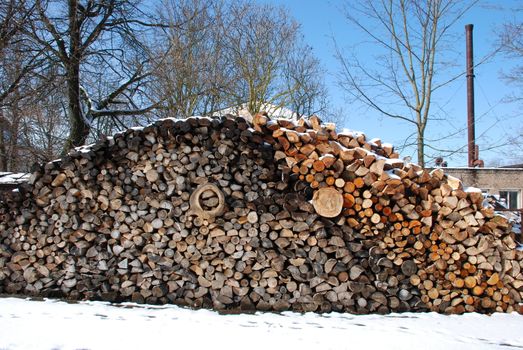 Snow covered firewood pile next to boiler house. Preparing for the cold season.