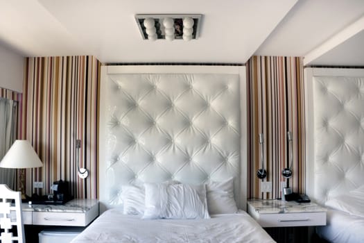 A modern white hotel bedroom with night stand