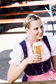 Bavarian woman in the beer garden with a glass of beer