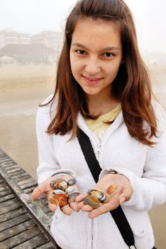 young cute teenage girl portrait on seaside at spring with shells in hands