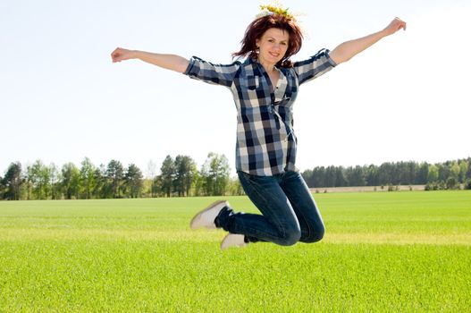 Happy young woman is jumping in a field 
