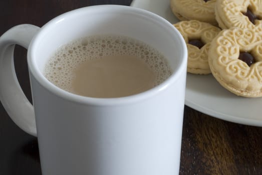 a mug of white tea and plate jam biscuits