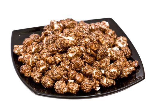 chocolate popcorn on the black plate isolated on white