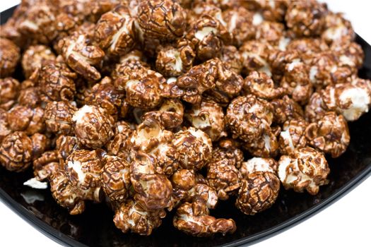 chocolate popcorn on the black plate isolated on white