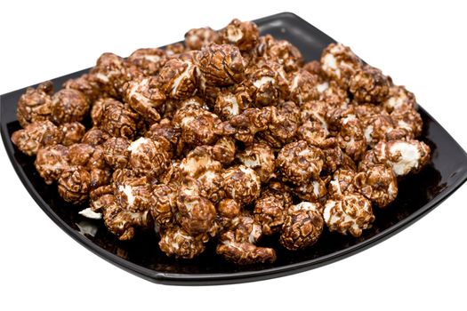 chocolate popcorn on the black plate isolated on white