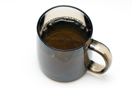 a transparent black cup with tea and tealeafs