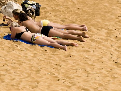 Women in bikinis sunbathing ona beach in spring in Malta