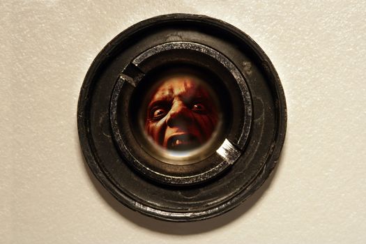 Looking through the peephole of an apartment door at an angry fellow on the other side.
