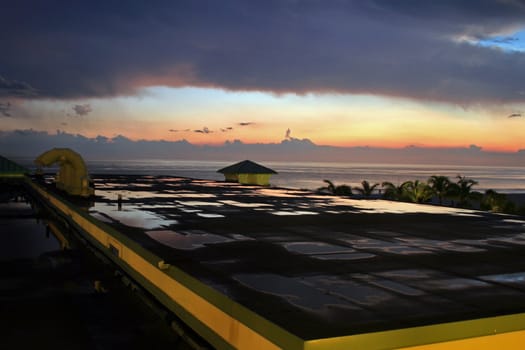 A sunset reflected in the puddles on a building.