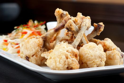 Fried chicken wings garnished with fresh vegetables with Teriyaki sauce