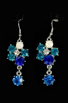 Beautiful earrings with colorful gems on black background