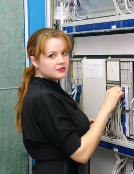 woman engineer serves equipment on digital telephony station 