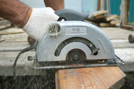 The assembler saws a board on a marking.