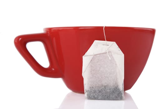 reflection of Red Ceramic cup with tea bag on white background