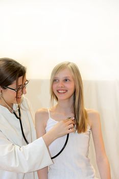 Young doctor or nurse examined laughing girl and listens to it - Copy Space