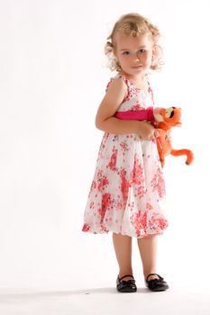 Little blonde girl in fashionable dress and soft toy in the hand