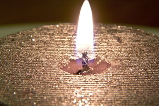 Sparkling silver and gold colored candle burning brightly