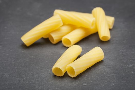 Dried Rigatone pasta on dark grey work surface.