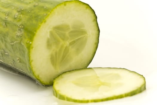 Close-up picture of a cucumber and a cucumber slice on a white background