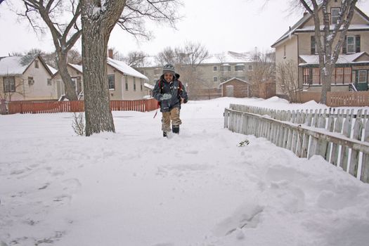 A young boy running home in the snow after being dropped off from school