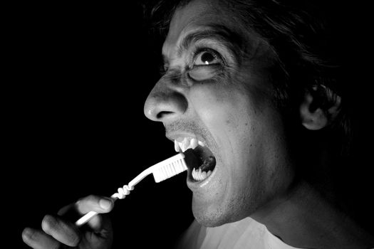 A man like a vampire brushing his teeth, in dramatic lighting.