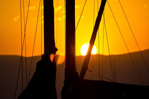 Golden sunset and sailboats - ropes, sail and sun behind the mountain