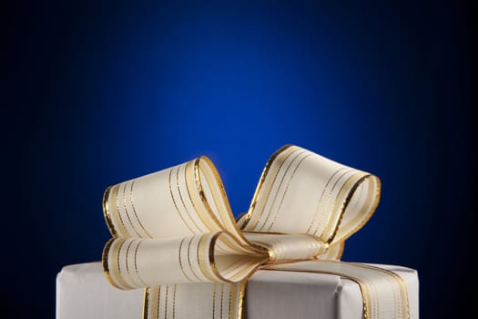 White gift box with bow ribbon on blue background 