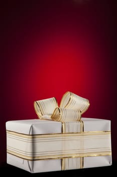 White gift box with bow ribbon on red background 