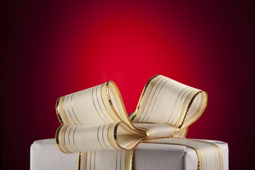 White gift box with bow ribbon on red background 