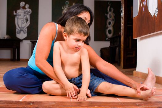 Mother gently teaching her small boy his first yoga notions